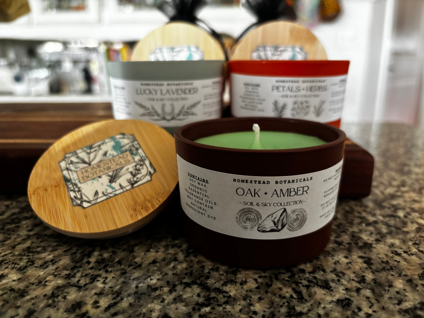Candle with a wooden lid on a countertop, surrounded by other candles and containers.
