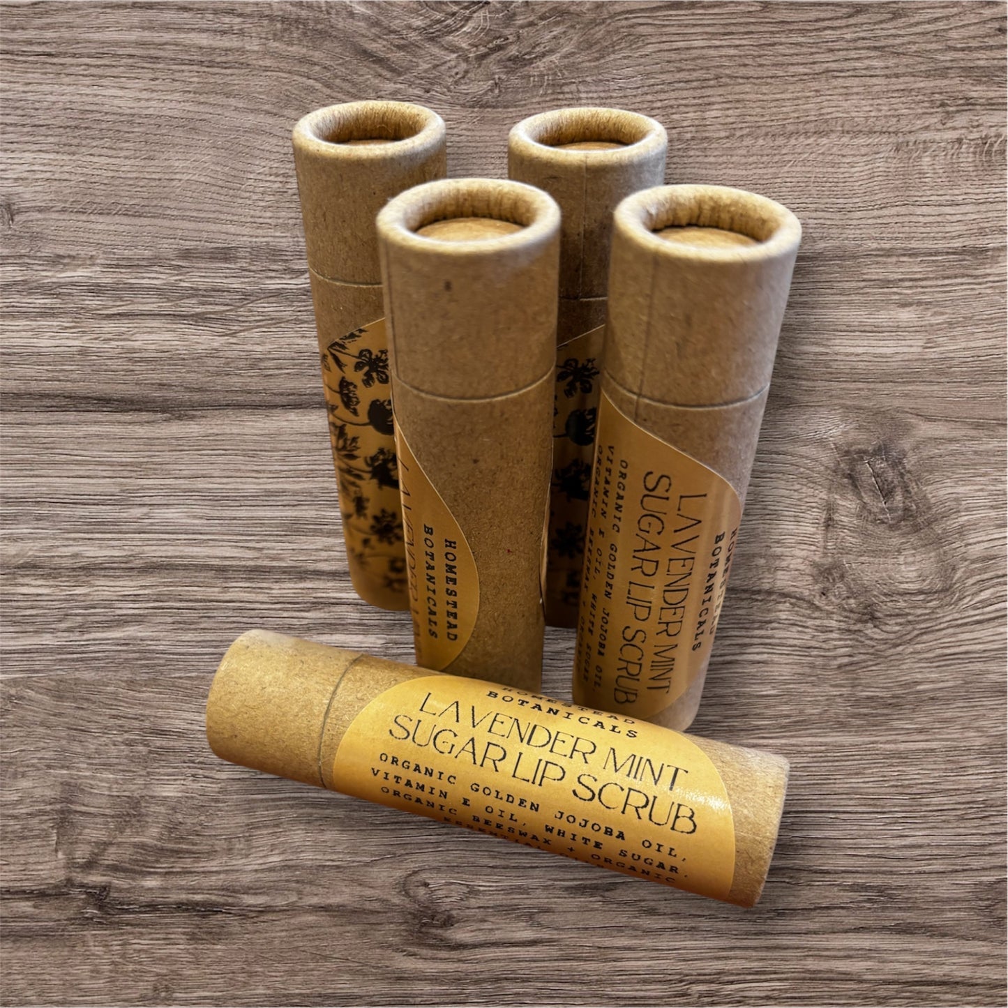 Set of brown paper lip scrub containers on a wooden surface